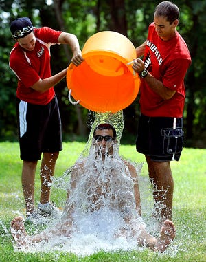 Counselor Brian Iafolla receives a bucket of water from Tim Collins, left, and Mark Nickerson at the conclusion of a water run game at Pilgrim Day Camp in Framingham Thursday.