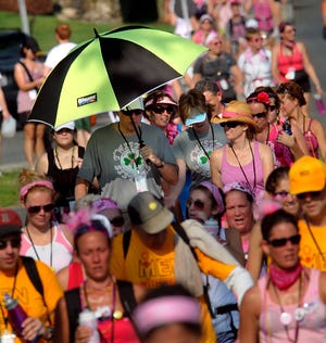 One walker uses an umbrella as a group travels down a steamy West Central St. in Natick during the Susan G. Komen 3-Day for the Cure Friday morning.