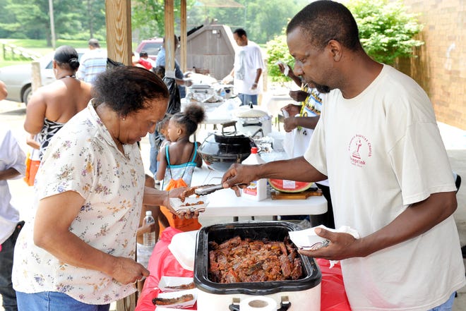 Mike Tate of Peoples Baptist Church serves Esther Brown a rib during Happenin' in the Hood an event held at the Southeast Community Center.