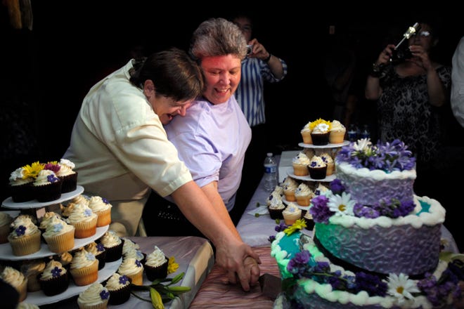 Kitty Lambert, right, and Cheryle Rudd cut their wedding cake at their reception before their wedding in Niagara Falls Sunday. Mayor Paul Dyster performed the ceremony just after midnight.