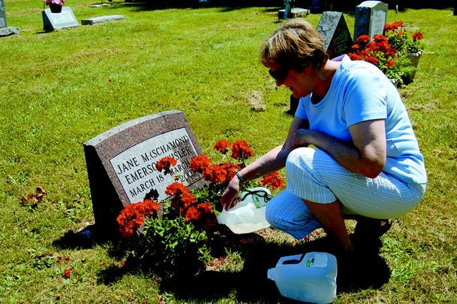Eddie Perry of Cheboygan waters the geraniums on a grave in Mt. Calvary Cemetery. She says she tries to come out for a visit every week.