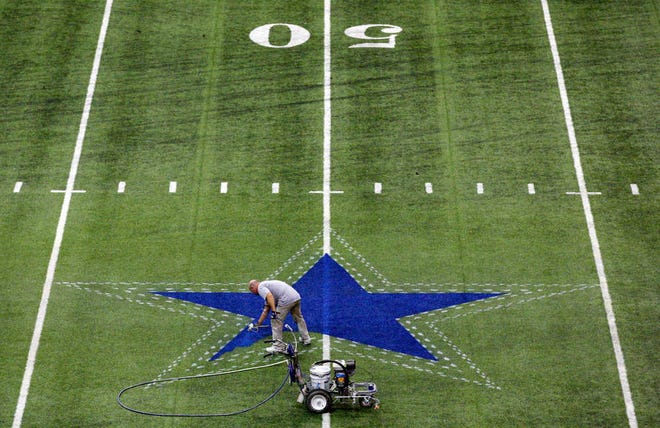 A worker paints the star on the 50-yard line in the Alamodome on Monday in San Antonio, where the Cowboys will open training camp on Thursday.