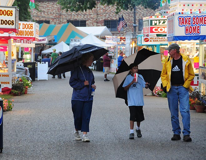 Michelle Buurma, left, Micah Sage and Bill Buurma brave the weather Wednesday, July 27, 2011, to enjoy the Ottawa County Fair in the rain.
