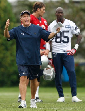 New England Patriots head coach Bill Belichick calls a play during the NFL football team's training camp yesterday. At rear is wide receiver Chad Ochocinco (85) and quarterback Tom Brady.