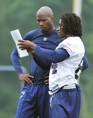 Chad Ochocinco and Deion Branch look over plays during Friday morning session at Gillette Stadium in Foxboro.