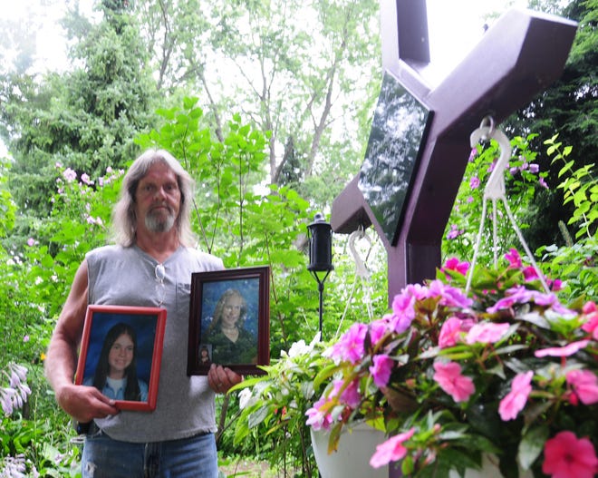 Perry Carr holds pictures of his daughter Samantha Carr and his step daughter Ariel Fazer, who died in a fire in Holland, next to a mural he made dedicated to the girls who died in the fire.