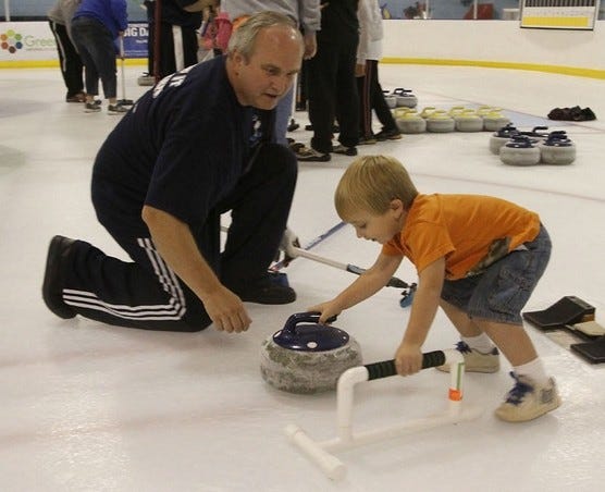 Bill Marshall, with the Palmetto Curling Club, shows Aiden Gross, 3, how to throw a stone during the clubs open house at the Pavilion Recreation Complex in Taylors, S.C. last week. The open house was a chance for people not familiar with curling to get an introduction to the sport. The club meets once a week. Currently the club does not have a junior league for anyone younger than 14.