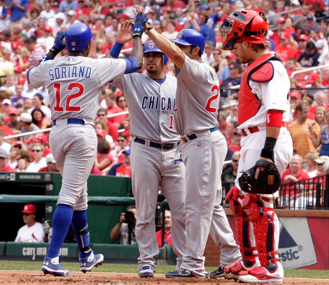 Chicago Cubs' Alfonso Soriano (12) celebrates with teammates Carlos Pena (22) and Geovany Soto (18), as St. Louis Cardinals catcher Yadier Molina watches, after Soriano hitting a three-run home run in the first inning of a baseball game, Saturday, July 30, 2011 in St. Louis.