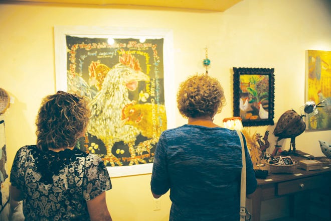 Patrons view a batik chicken art piece by local artist Wendy Tatter on Saturday evening at W.B. Tatter Studio Gallery on Saturday night.