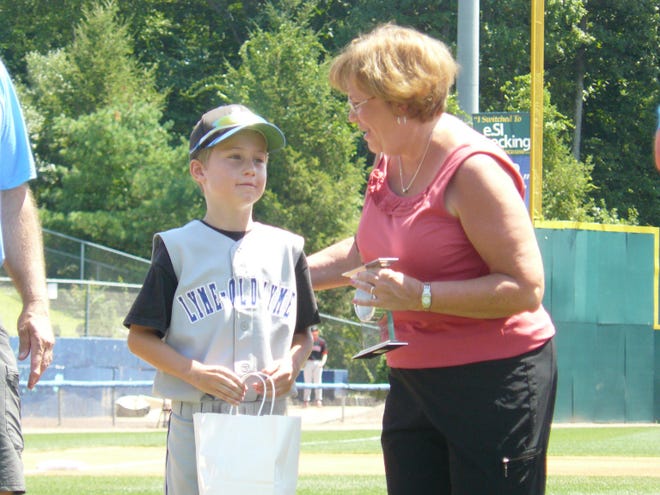 Joanne McDonald, right, accepts an award from Lyme-Old Lyme Little League player Grady Sheffield on Sunday at Dodd Stadium during a ceremony on Christopher Potvin Day. Joanne McDonald accepted the award on behalf of her late husband Jack, who umpired for years at the Christopher Potvin Baseball Tournament and served on the Board of Directors.
