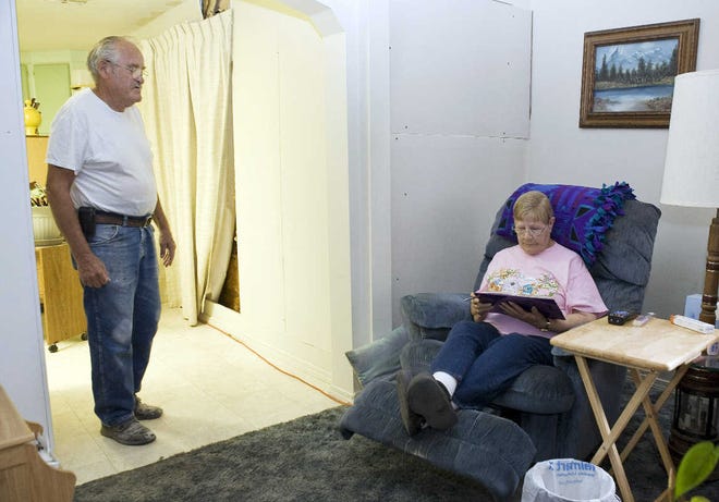 John Pangburn watches his wife, Wanda, work crossword puzzles on a hot summer day in their home in Mulhall, Okla. "I can’t take the heat like my husband can," said Wanda.