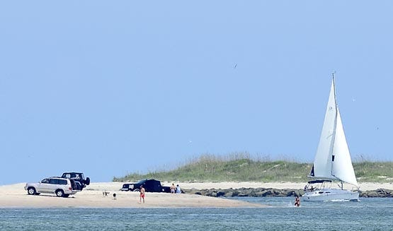 Beachgoers enjoy a day on Porpoise Point as a sailboat returns from the Atlantic Ocean through the St. Augustine Inlet on Wednesday. By PETER WILLOTT, peter.willott@staugustine.com