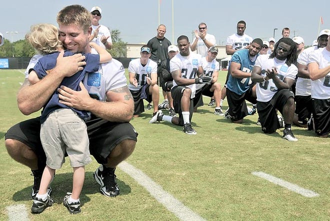 Jacksonville Jaguars center Brad Meester hugs Luke Akerstrom, 6, as players and coaches applaud after practice Thursday in Jacksonville. Meester and Luke have become friends after Meester's visits to Wolfson Children's Hospital and Brooks Rehabilitation the last eight months after Luke began having seizures. By WILL DICKEY, Morris News Service