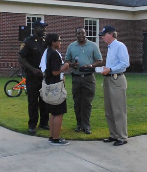 Hardeeville High School senior Tameka Daniels collects from police Chief Richard Nagy the laptop computer donated by Mayor Bronco Bostick and his wife as Capt. Arnold Middleton looks on. Two computers were handed out to winners of a drawing.