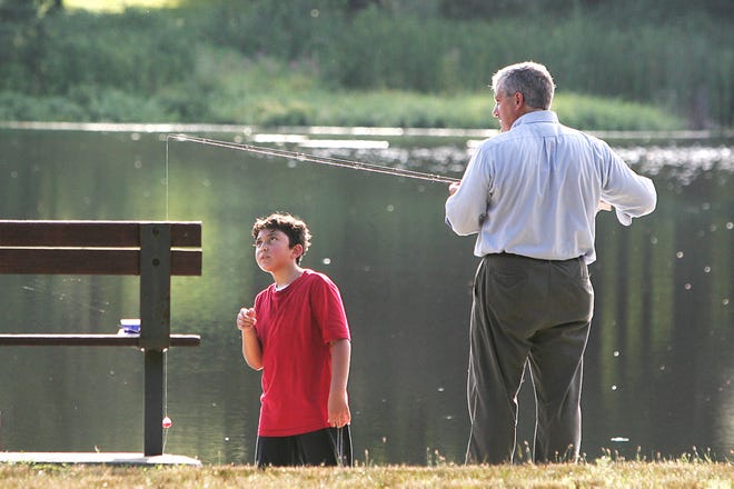 Blas Cerda Jr., 9, of Milford, checks his father, Blas Sr's fishing line technique during a fishing lesson at Louisa Lake in Milford yesterday.
