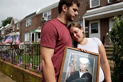 Charles Strange III, left, and his sister, Katelyn, hold a photo of their brother, Petty Officer First Class Michael Strange. Petty Officer Strange was a Navy SEAL killed in a helicopter crash in Afghanistan last week.