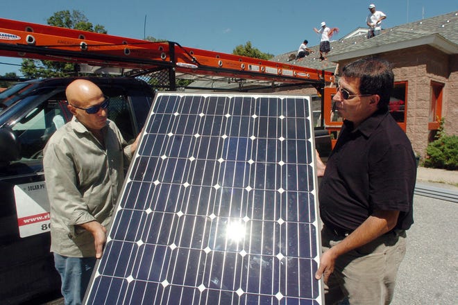 GRISWOLD 8-11-2011 JOHN SHISHMANIAN Phil Anthony, Griswold first selectman, right, is shown a solar panel by Peter Spinella of DCS Energy Thursday before panels were installed on the roof at Griswold Volunteer Fire Company. John Shishmanian/ NorwichBulletin.com