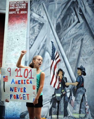 Alexis Gentile, 10, of Framingham cheers for passing drivers to beep their horns. Alexis is the daughter of Newton firefighter Mike Gentile. The Bower family is displaying a mural in the front yard of their Edgell Road home depicting three firefighters raising the American flag at ground zero after the 9/11 terrorist attacks in New York City.