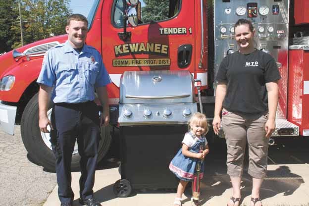 The Kewanee Community Fire Department is preparing for their annual fund-raising breakfast at the Kewanee Municipal Airport. Firefighter Ellis Ericson, left, poses with the stainless-steel gas grill which will be raffled during the breakfast. Representing MTD Installations Inc., which donated the grill, are Heather Dana and her 2-year-old daughter, Lauren.