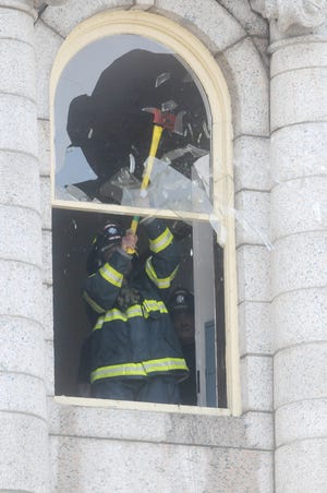 A Taunton firefighter breaks out a city hall window. Several Taunton Fire Department trucks blocked the intersection outside Taunton City Hall this morning, Aug. 17, 2010, in an attempt to stop a smoking fire from spreading out of control.