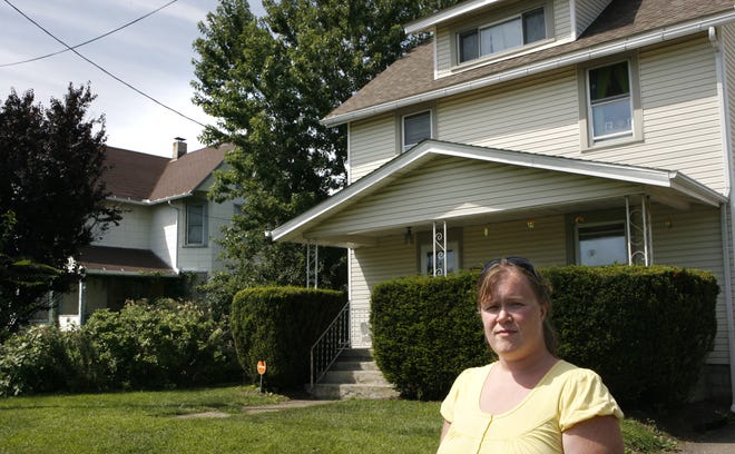 Laura Mann stands in front of her house on 12th Street SW next to an abandoned house.