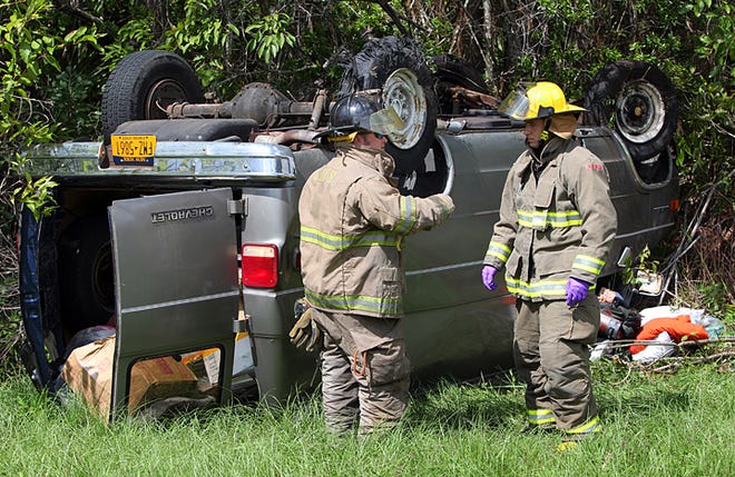 St. Johns County Fire Department engineer Scott Barnwell, left, investigates a possible fuel leak with firefighter/paramedic Matthew Peterson following a rollover crash Thursday. By DARON DEAN, daron.dean@staugustine.com