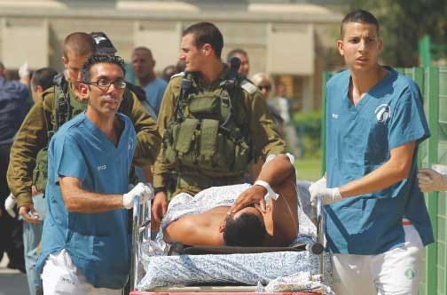 Israeli medics evacuate a person wounded in one of several
attacks in the Arava desert, to the Soroka hospital in Beersheba,
southern Israel, Thursday.