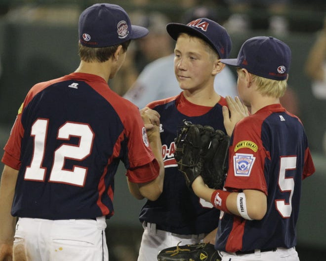 Clinton County, Pa., pitcher Alex Garbrick, center, is congratulated by Talon Falls (12) and Cole Reeder after reaching his pitch limit in the sixth inning of a 2-0 victory over Cumberland, R.I. Just above their Little League patch, players are all wearing yellow patches on their left shoulder that read: "I won't cheat!" It's a pledge for today and a goal for the future, when the choices won't be so clear.