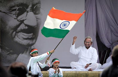 A girl waves an Indian flag and another sings a patriotic song beside India's anti-corruption crusader Anna Hazare, right, on Sunday.