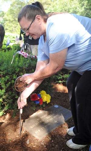 Victoria Smith-Fitts places a new marker on her husband’s grave, Army Staff Sgt. Richard A. Fitts, at Mount Vernon Cemetery in Abington on Monday during a dedication ceremony to replace stolen grave markers from veterans’ graves. Fitts was killed in action in the Vietnam War.