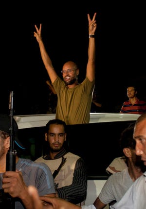 Moammar Gadhafi's son, Seif al-Islam waves to troops loyal to his father in Tripoli, Libya, Tuesday, Aug. 23, 2011. Al-Islam, who was earlier reported arrested by Libya's rebels, turned up early Tuesday morning at a hotel where foreign journalists stay in Tripoli, then took reporters in his convoy on a drive through the city. (AP Photo/Dario Lopez-Mills)