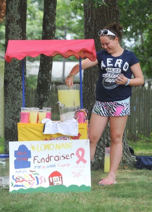 Kaleigh McCormack, 12, of Brockton stirs lemonade with a spoon during her charity fundraiser on Fern Avenue in Brockton in July 2011.