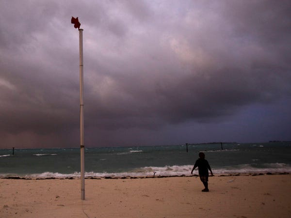A boy walks on the beach as a red flag flies and bands of rain and wind come through from Hurricane Irene in Nassau, on New Providence Island in the Bahamas on Wednesday. Associated Press