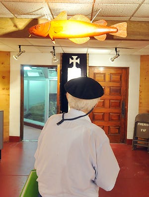 Dr. Manuel da Silva looks at the wooden codfish hanging at the Dighton Rock Museum.