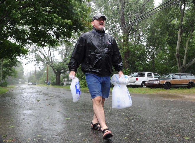 John Boyle of Bridgewater carries bags of ice to his Pleasant Street home in Bridgewater after his power was knocked out by Tropical Storm Irene on Aug. 28, 2011.