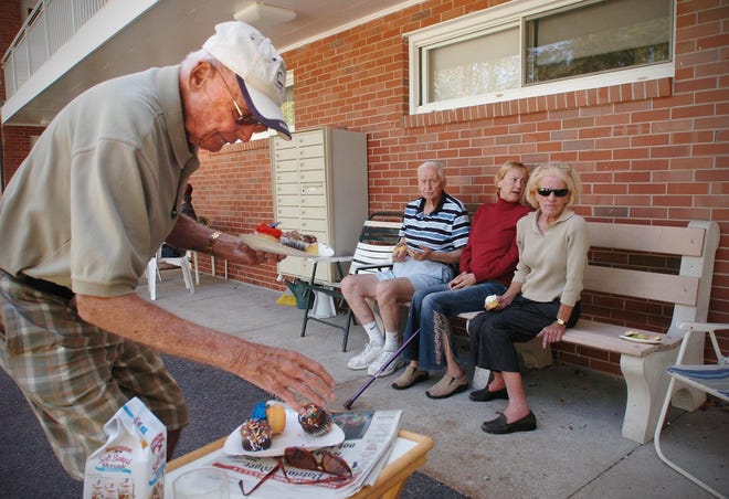 John MacNeil, left, helps himself to cupcakes as he sits outside with neighbors at the Lincoln Park Housing Authority apartment complex on Tuesday, Aug. 30, 2011, two days after Hurricane Irene cut off their electricity.