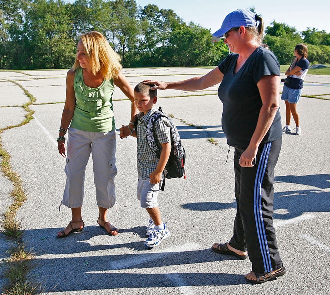 Christian Sheehey,6, who was entering first grade, gets a pat on the head from mom Tara McLean as teacher's aide Cathy Richardson takes his hand at the Daniel Webster School in Marshfield on Wednesday, Aug. 31, 2011.