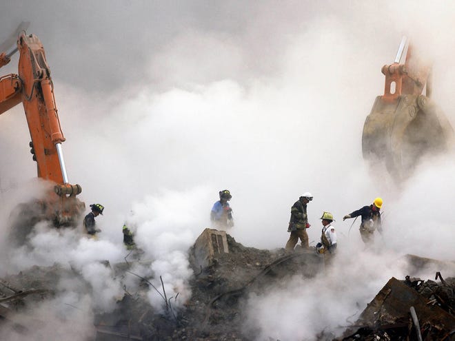 In this Oct. 11, 2001 file photo, firefighters make their way over the ruins of the World Trade Center through clouds of smoke at ground zero in New York. A decadeÕs worth of study has answered only a handful of questions about the hundreds of health conditions believed to be related to the tons of gray dust that fell on the city when the trade center collapsed, from post-traumatic stress disorder, asthma and respiratory illness to vitamin deficiencies, strange rashes and cancer. .(AP Photo/Stan Honda, Pool)