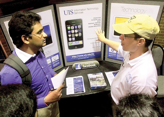 Krish Kilaru, left, speaks with Gary Bach while picking up job applications at the University of Illinois Technology booth during a job fair at the University of Illinois Springfield campus on Thursday in Springfield, Ill. Employers added no net workers last month and the unemployment rate was unchanged, a sign that many were nervous the U.S. economy is at risk of slipping into another recession.