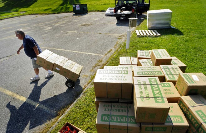 Edward Munroe, Woodstock emergency management director, uses a hand cart yesterday to carry boxes of MREs (meals ready to eat) for overnight storage at Town Hall, after a day of providing them to residents still without power following Tropical Storm Irene.