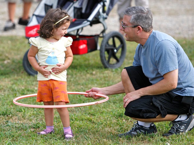 Molly Chace, 3, smiles at her dad, Bill, both of Westboro, as he helps her learn to play with a Hula Hoop at the 4H Fair in Middleboro on Saturday.