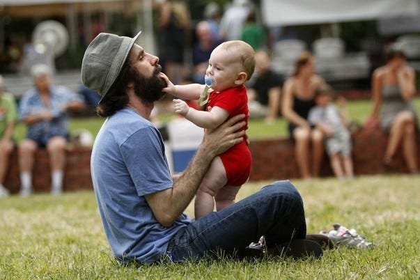 Andrew Schaer, owner of Hear Again Music & Movies, plays with his son Elliott, 1, in the field at the Bo Diddley Downtown Plaza during the Labor Daze Fest in Gainesville on Sunday.