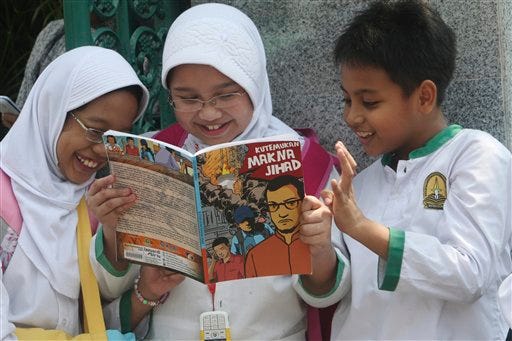 Students read a comic book with an anti-extremist theme at a primary school Friday, Sept. 9, 2011 in Jakarta, Indonesia. The real life adventures of former al-Qaida-linked terrorist Nasir Abas have become a new comic book in Indonesia, chronicling his transformation from militant to invaluable ally in the fight against terrorism.