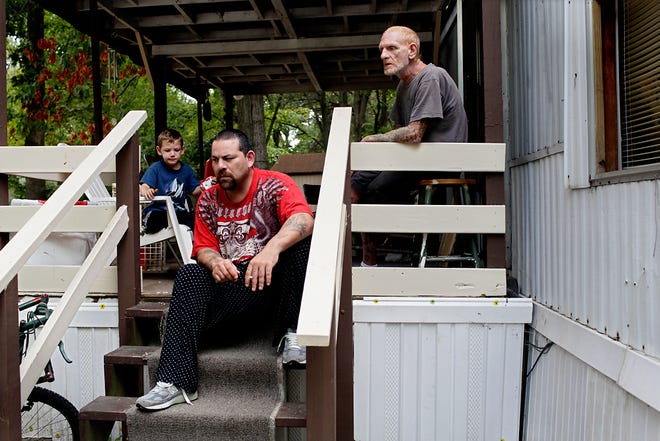 From right, James Chapman Sr., Trinidad Rodriguez and James Chapman Jr. sit on the porch of a trailer Friday in Columbia Regency Mobile Home Park. Residents learned last week that the owner of the park wants to rezone the property and create a student housing complex.