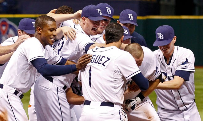 Tampa Bay Rays' Evan Longoria, second from right, is swarmed by teammates after his game-winning RB-single in the eleventh inning of a baseball game against the Boston Red Sox, Saturday, Sept. 10, 2011, in St. Petersburg, Fla. The Rays won 6-5. (AP Photo/Mike Carlson)