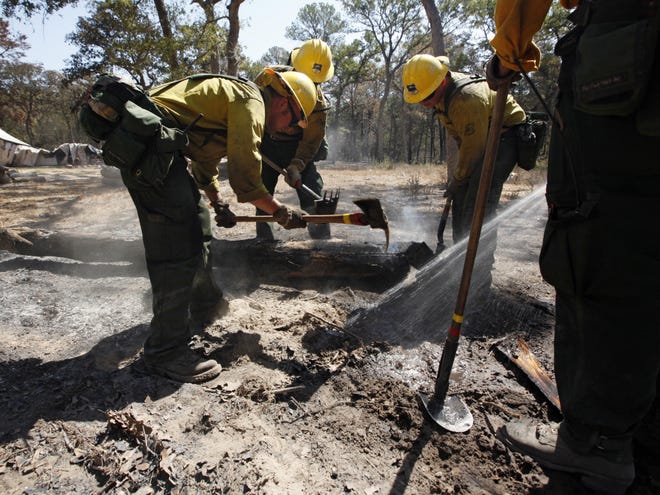 A fire fighting crew from the Lassen National Forest in Calif., clean up hot spots after the destructive wildfire in Bastrop, Texas, Sept. 10, 2011. Officials in Texas say fire crews are making progress fighting a massive Texas wildfire but concerns about hotspots are keeping thousands of residents in the Bastrop area from returning home. (AP Photo/Eric Schlegel)