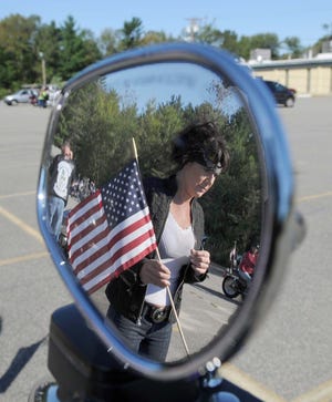 Birgitt Johnston of Lakeville is reflected in a rear view mirror as she holds Old Glory.