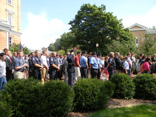State police officers, above, and other service people and community members watch the flag being raised. The flags, below right, were raised by students who were also in the service.
 DAILY NEWS/HOLLY RONEY