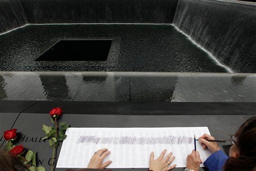 Rita Cullen, right, traces her son firefighter Tom Cullen's name from the engraving at the south pool of the National September 11 Memorial during a ceremony marking the 10th anniversary of the attacks at World Trade Center, Sunday, Sept. 11, 2011 in New York. (AP Photo/Mary Altaffer)