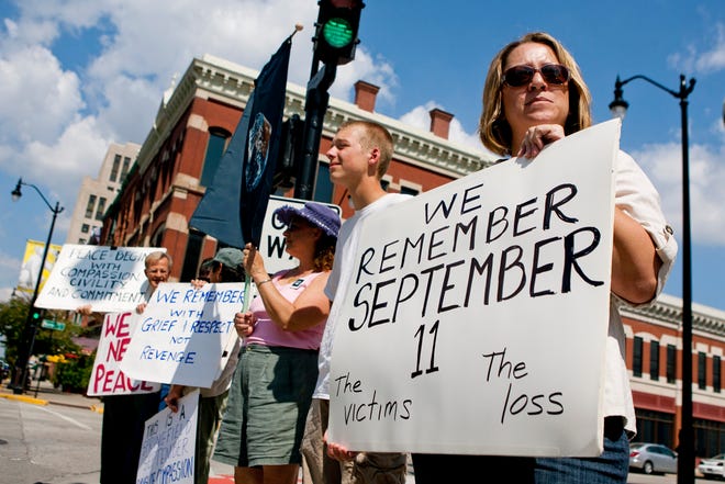 Tara Puma, right, of Springfield, Ill., stands with other supporters during a public vigil for the victims of 9/11 held outside the Paul Findley Federal Building in Springfield, Ill., Sunday, Sept. 11, 2011.